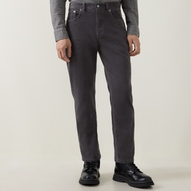 Model wearing Gant Cord 3049 Jeans in Dusky Anthracite, styled with a grey knit top and black leather shoes.