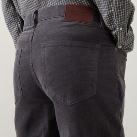 Model wearing Gant Dusky Anthracite cord jeans, close-up rear view showing back pockets and leather logo patch, styled with check shirt.