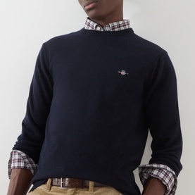 Model wearing Gant Navy Wool Crew Neck jumper with logo embroidery, styled over a red checked shirt with chinos.