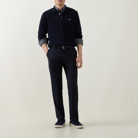 Model wearing Gant Shield Logo Fine-Knit Polo Sweater in navy, styled with dark trousers and slip-on shoes.