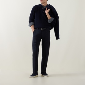 Model wearing Gant Shield Logo Fine-Knit Polo Sweater in navy, styled with dark trousers, chambray shirt and white sole trainers.