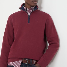 Model wearing Gant Deep Grape Wine cotton half-zip sweatshirt, styled with a striped shirt and jeans.