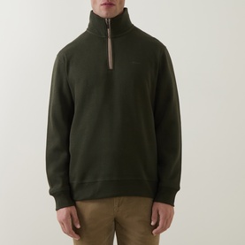 Model wearing Gant dark moss green cotton half-zip sweatshirt with ribbed cuffs and hem, styled with tan trousers