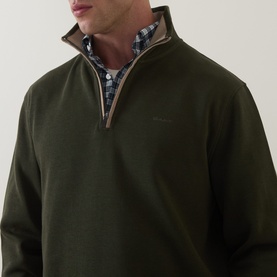 Model wearing Gant dark moss green cotton half-zip sweatshirt, styled over a blue checked shirt