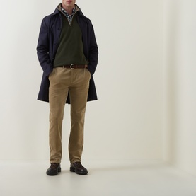 Model wearing Gant dark moss green sweatshirt, layered under navy overcoat with checked shirt, styled with tan chinos and dark loafers.