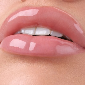 Gisou lip gloss swatch shown on lips in a sheer rosy pink shade with high-shine glossy finish