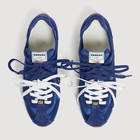 Sandro blue suede trainers with white laces, gold logo detail, and cream rubber sole, seen from above
