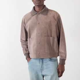 Model wearing JW Anderson Mouse Grey suede casual jacket with spread collar, snap fastening, and patch pockets, styled with light wash jeans.