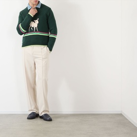 Model wearing JW Anderson Sheep Stripe Sweater in Dark Fir with sheep motif and stripe detail, styled with cream trousers and dark loafers