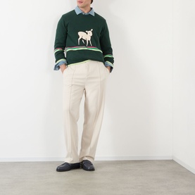 Model wearing JW Anderson Sheep Stripe Sweater in Dark Fir, crew neck with sheep motif and stripe detail, styled with cream trousers and black loafers