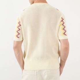 Model wearing JW Anderson Chevron Pattern Sweater in ivory with multicolour zigzag sleeve detail, ribbed trims, and short sleeves. Back view.