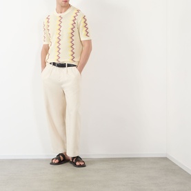 Model wearing JW Anderson Ivory Chevron Pattern Sweater with cream trousers, black belt, and dark brown sandals.