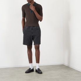 Model wearing JW Anderson Military Green cotton-cashmere polo with dark washed shorts and black loafers.