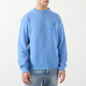Model wearing JW Anderson Ribbon Anchor Logo Sweatshirt in washed blue, crew neck, ribbed trims, styled with light-wash jeans