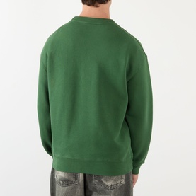 Model wearing JW Anderson Scattered Logo Sweatshirt in green, crew neck with ribbed trims, back view, styled with grey jeans.