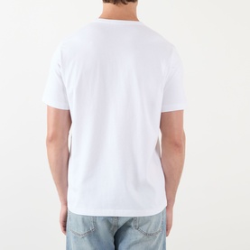 Model wearing JW Anderson Anchor Logo T-Shirt in white, round neck, short sleeves, styled with light wash jeans. Back view.
