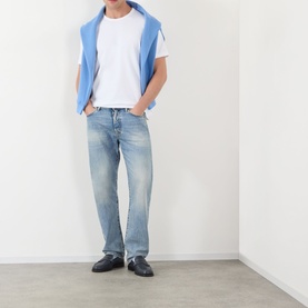 Model wearing JW Anderson Anchor Logo T-Shirt in white, styled with light-wash jeans, a blue vest and black loafers.