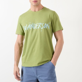 Model wearing JW Anderson Circular Logo T-Shirt in leaf green with blue logo graphic print, styled with light blue jeans.