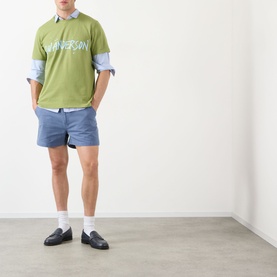 Model wearing JW Anderson Circular Logo T-Shirt in leaf green with blue shorts and navy loafers.