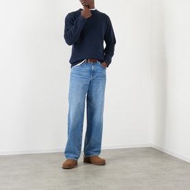Model wearing JW Anderson navy cotton sweatshirt with light blue wide-leg jeans, brown leather belt, and tan suede loafers