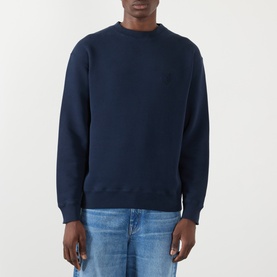 Model wearing JW Anderson navy cotton crewneck sweatshirt with subtle chest logo, styled with light blue jeans.