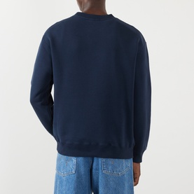 Model wearing JW Anderson navy cotton sweatshirt, back view, styled with light blue jeans.