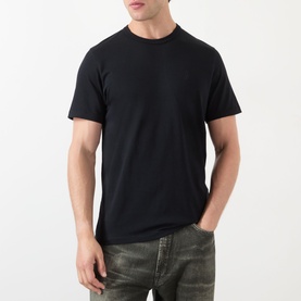 Model wearing JW Anderson Anchor Logo T-Shirt in black, round neck, short sleeves, styled with khaki jeans.