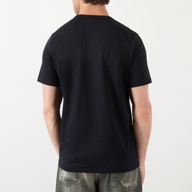 Model wearing JW Anderson Anchor Logo T-Shirt in black, rear view, round neck, short sleeves, styled with khaki cargo trousers.