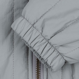 Konges Sl&oslash;jd light blue children's jacket close-up showing elasticated cuff and gold zip detail on quilted fabric.