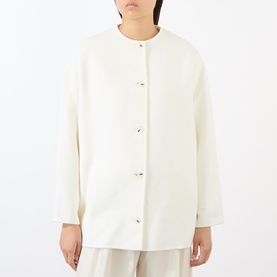 Model wearing Loulou Studio ivory wool-cashmere coat with collarless neckline, long sleeves, and button fastening.