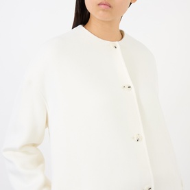 Model wearing Loulou Studio ivory wool-cashmere coat with gold-tone snap buttons and collarless neckline.