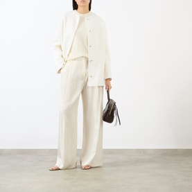 Model wearing Loulou Studio ivory wool-cashmere coat styled with matching wide-leg trousers and carrying a small dark brown bag.