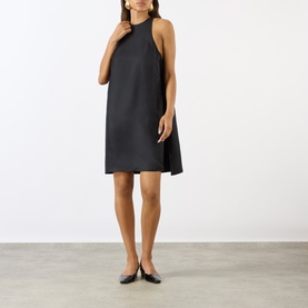 Model wearing Loulou Studio black silk dress with halterneck silhouette and A-line cut, styled with black ballet flats