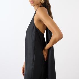 Model wearing Loulou Studio black silk dress with low open back, thin straps, and relaxed silhouette, side view