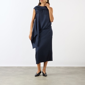 Model wearing Loulou Studio navy silk dress with draped shoulder detail, styled with black flat shoes