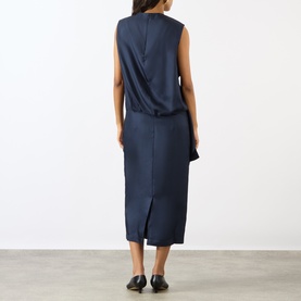 Model wearing Loulou Studio navy silk dress, back view, sleeveless with draped detail and midi length, styled with black flat shoes