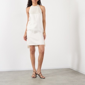 Model wearing Loulou Studio ivory silk halterneck mini dress with open back, styled with black strappy heeled sandals