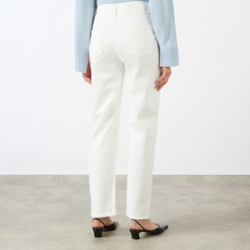 Model wearing Loulou Studio ivory straight-leg jeans, rear view, styled with a light blue knit top and black heeled mules.
