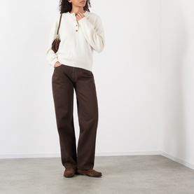 Model wearing Loulou Studio brown wide-leg cotton jeans, styled with a cream henley top and brown loafers, small shoulder bag