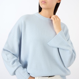 Model wearing Loulou Studio light blue cashmere knit sweater with crew neck, dropped shoulders, and ribbed cuffs.