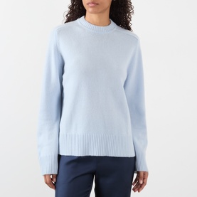 Model wearing Loulou Studio Baltra Knitted Sweater in light blue, crew neck, long sleeves, ribbed trims, paired with navy trousers.