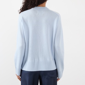 Model wearing Loulou Studio Baltra Knitted Sweater in light blue cashmere, crew neck, long sleeves, ribbed trims, back view, styled with navy