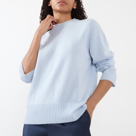 Model wearing Loulou Studio Baltra Knitted Sweater in light blue cashmere, crew neck with ribbed trims, paired with navy trousers.