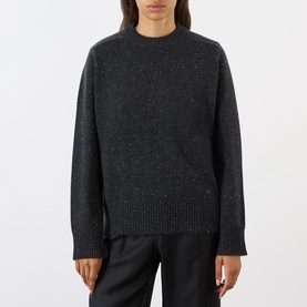 Model wearing Loulou Studio cashmere knit sweater in peppered anthracite, relaxed fit with crew neck, styled with black trousers.