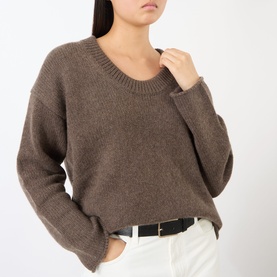 Model wearing Loulou Studio brown cashmere knit sweater with crew neck and relaxed fit, styled with white trousers and black belt.