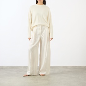 Model wearing Loulou Studio ivory cashmere knit top, styled with matching wide-leg cream trousers and nude sandals.