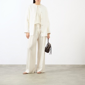Model wearing Loulou Studio ivory cashmere knitwear with matching wide-leg trousers and a small dark bag.