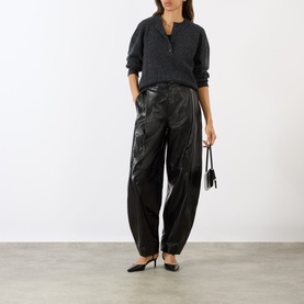 Model wearing Loulou Studio Malo Half-Buttoned Sweater in Ivory, styled with black leather trousers and heels, carrying a small black bag.