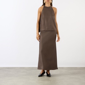 Model wearing Loulou Studio dark brown silk maxi skirt, styled with matching halterneck top and black flat shoes.