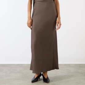 Model wearing Loulou Studio dark brown silk maxi skirt with flared hem, styled with black pointed-toe flats